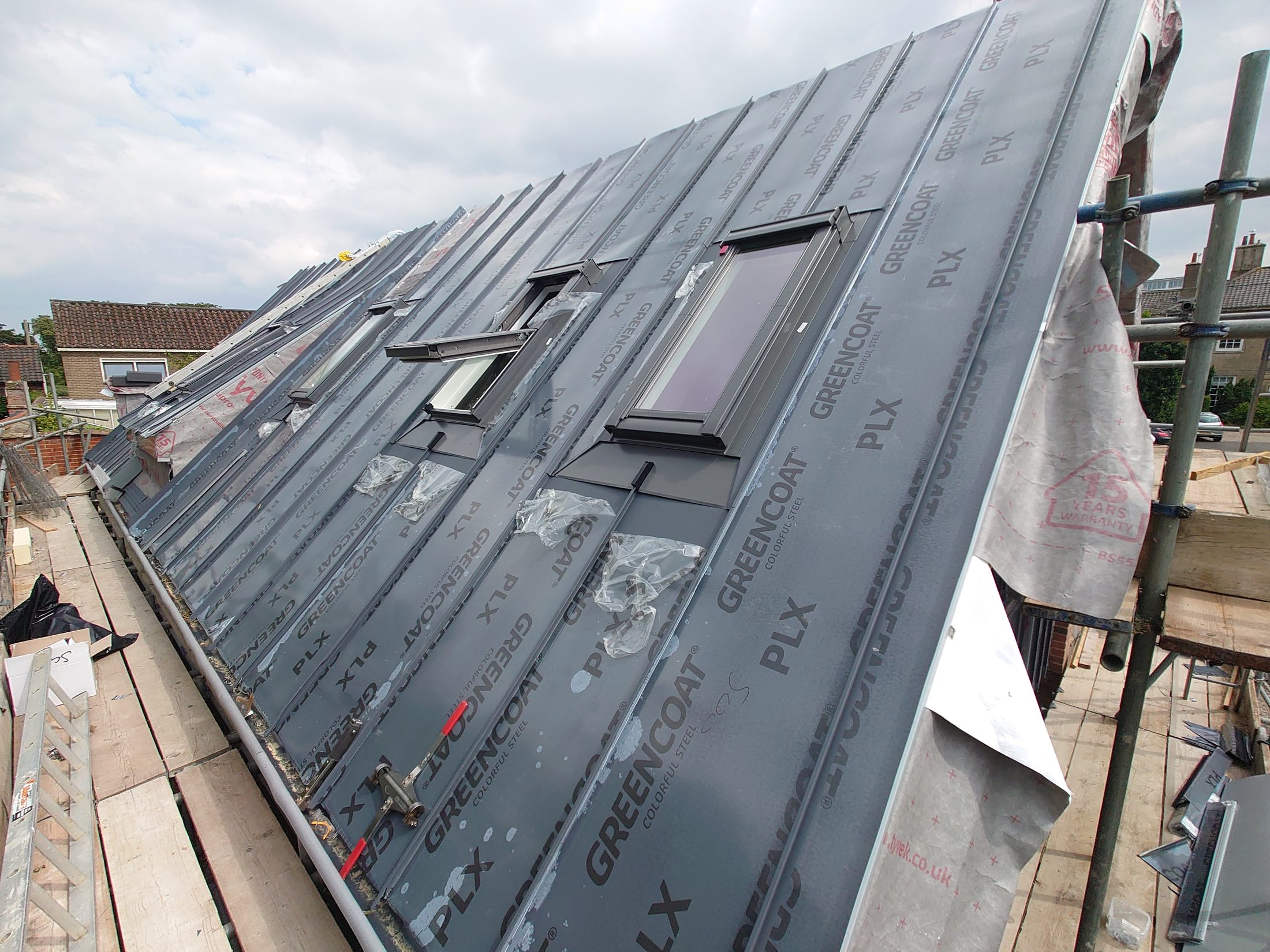 Copperclad standing-seam roof during installation, showing the build-up and rooflight interfaces